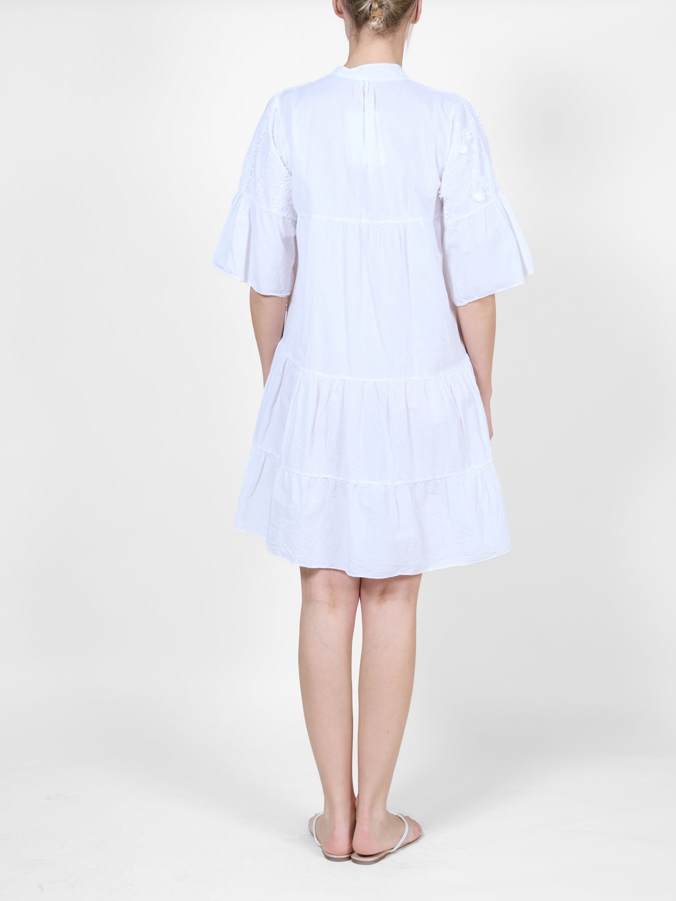 Robe blanche ornée de volants et de broderies florales