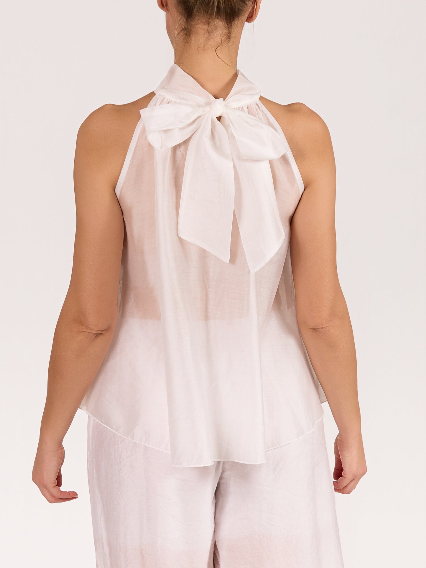 Blouse blanche sans manches avec nœud et volants à l’avant