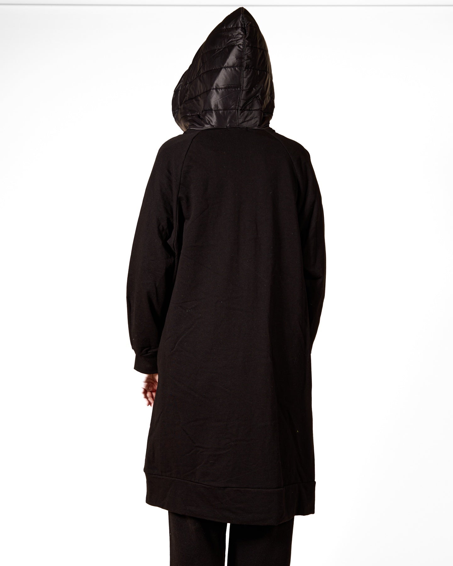 Manteau noir à manches longues et fermeture éclair sur le devant, en tissu matelassé.